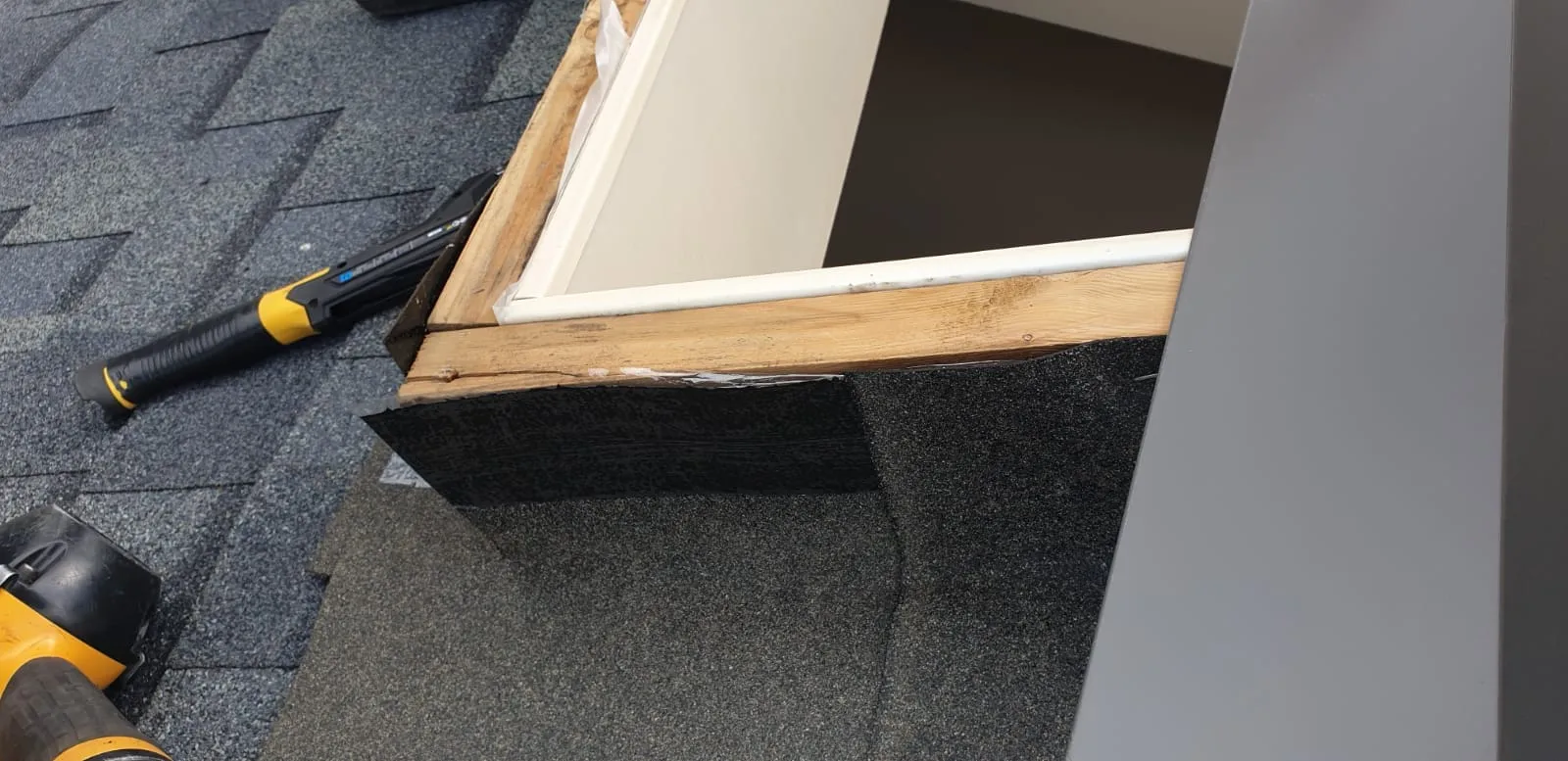 Skylight flashing kit being fitted into the surrounding shingles